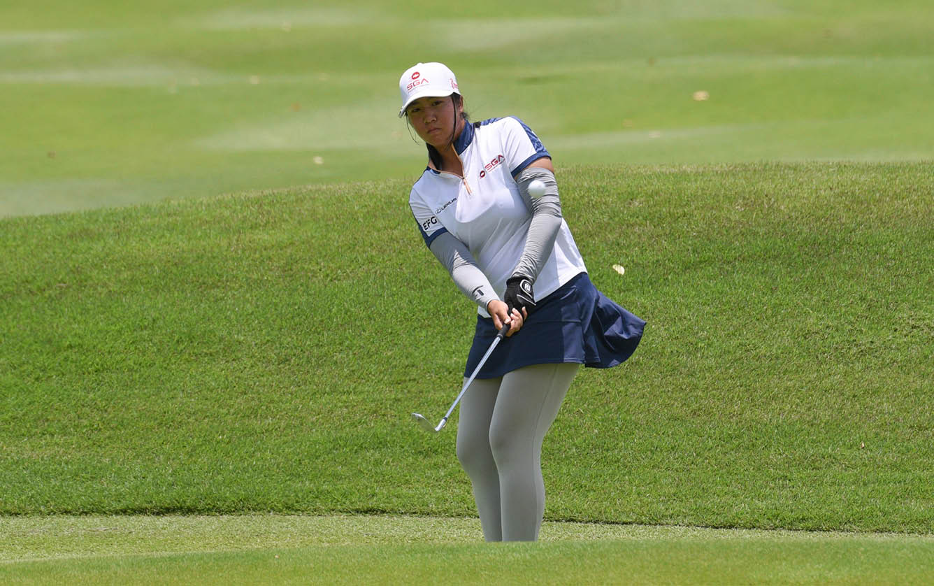 A woman in a white shirt and blue skirt is swinging a golf club on a green course. AI generated content