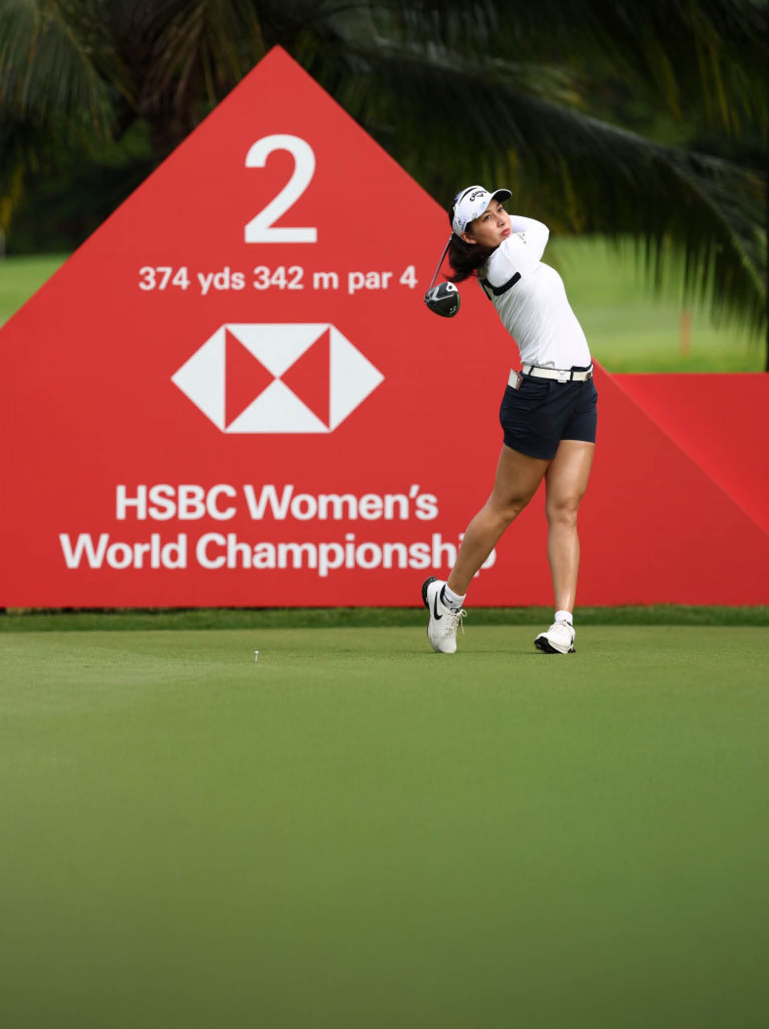 A woman is swinging a golf club at a red sign with the number 2 on it. AI generated content