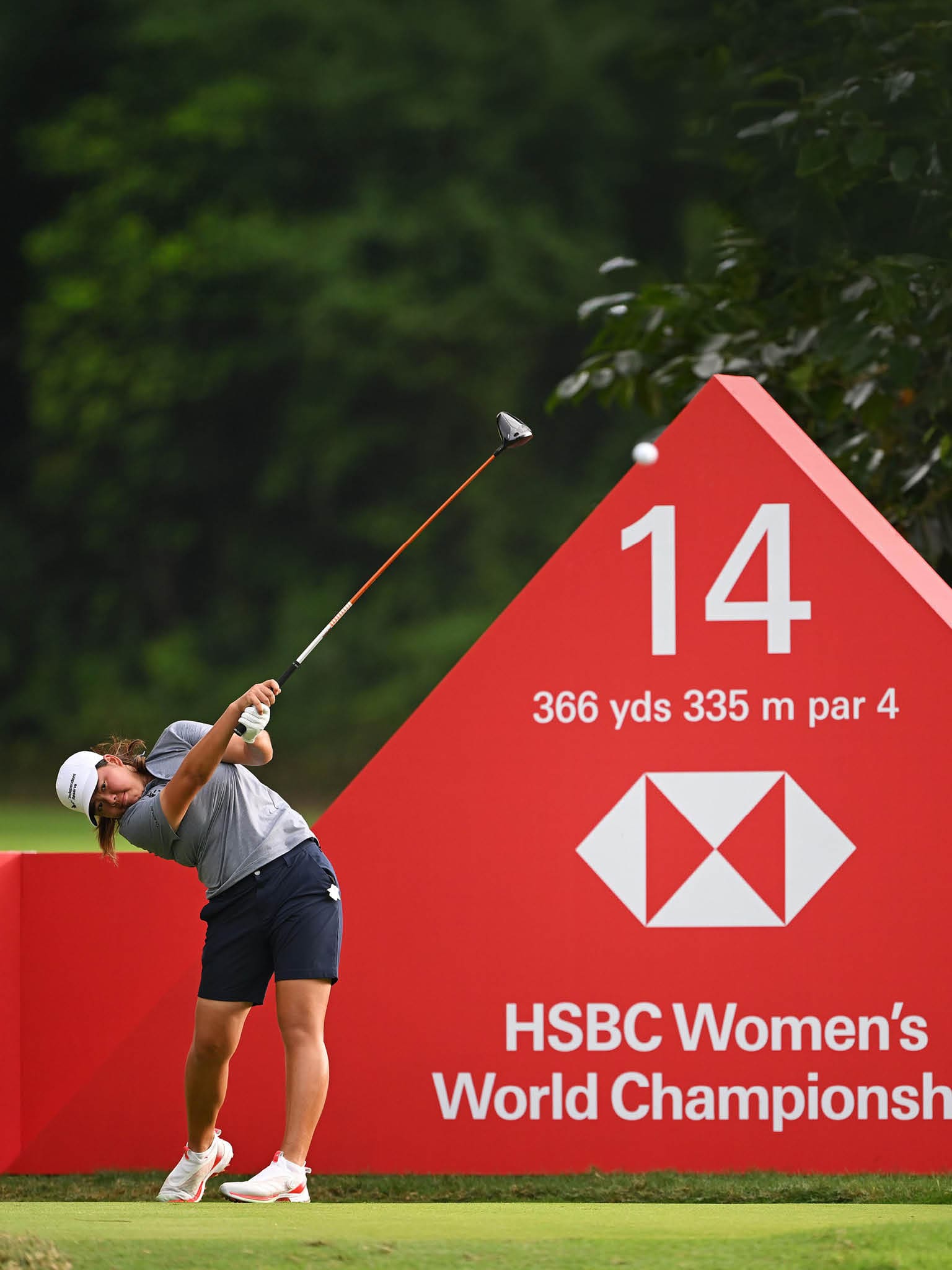 A woman is swinging a golf club at a ball on a golf course. AI generated content