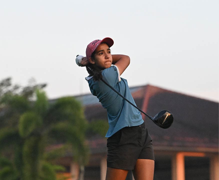 A woman in a blue shirt and red hat is swinging a golf club at a ball. AI generated content