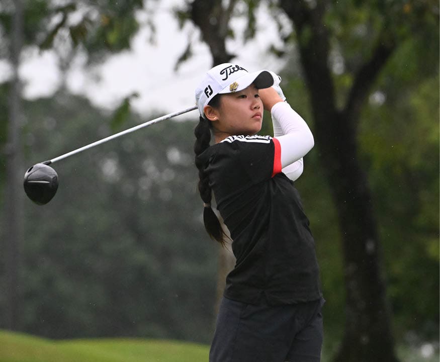 A woman in a black shirt and white cap is swinging a golf club at a ball. AI generated content