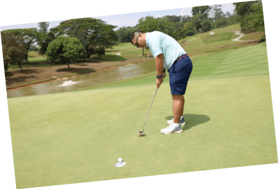 A man is playing golf on a green course. Description generated by AI